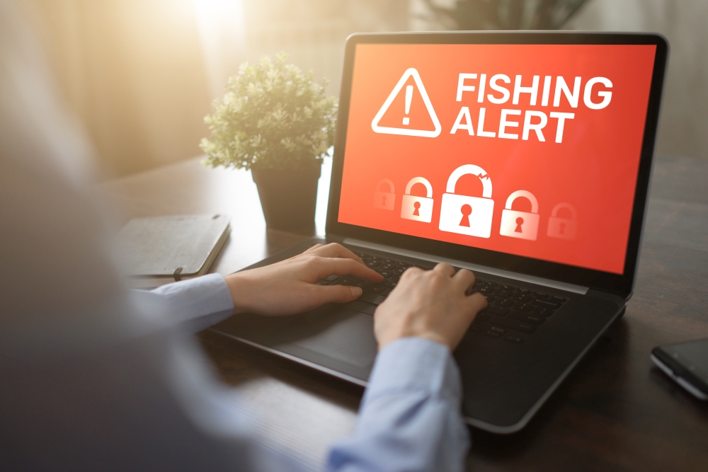 Ein Mann arbeitet am PC mit dem Schriftzug am Monitor Fisching Alert