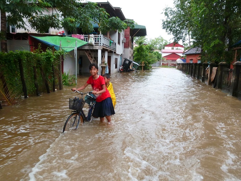 Ein Junge fährt das Fahrrad in der überfluteten Strasse in Bangladesch