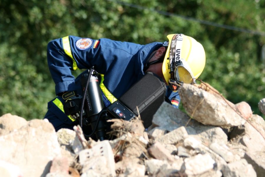Eine Einsatzkraft versucht, mit Hilfe einer Endoskopkamera ver-schüttete Personen zu lokalisieren.