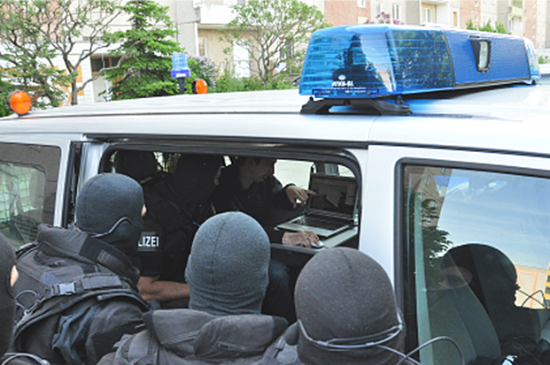 Polizisten in Schutzausrüstung vor Einsatzwagen