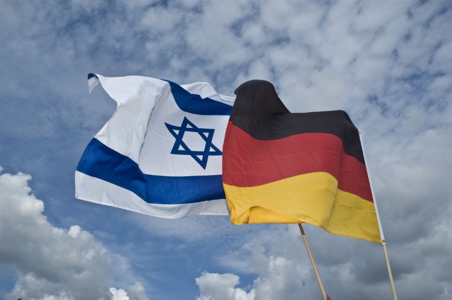Die Fahnen von Israel und Deutschland wehen gemeinsam vor blauem Himmel.