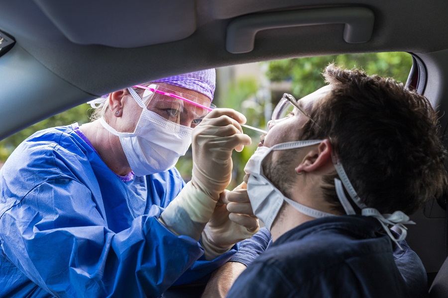 Bei einem Mann im Auto wird ein Coronaabstrich gemacht