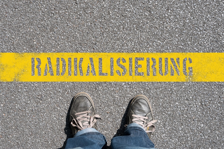 Ein Mensch steht vor dem Schriftzug Radikalisierung