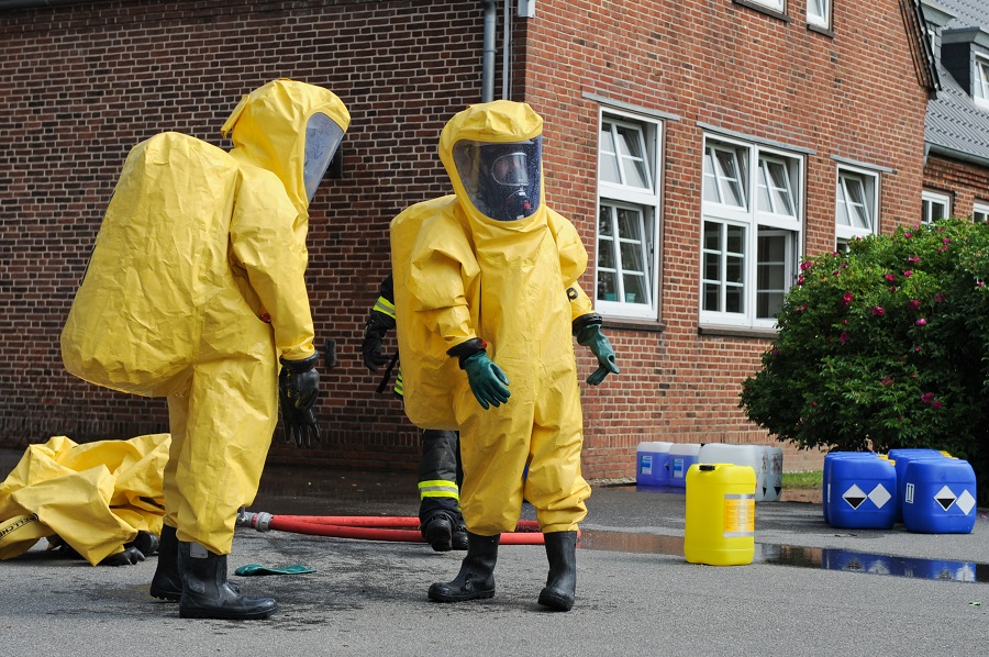 Einsatzkräfte in Chemikalienschutzanzügen beseitigen giftige Kanistern