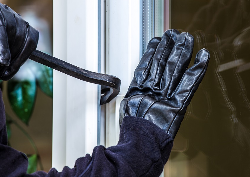 Ein Verbrecher bricht durch das Fenster ein.